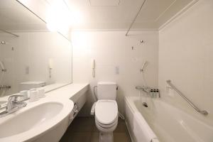 a white bathroom with a sink and a toilet and a tub at Smile Hotel Osaka Yotsubashi in Osaka