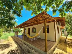 a house with a hammock on a deck at Casa Marfim - Privacidade, charme e conforto à 50m do rio in Caravellas