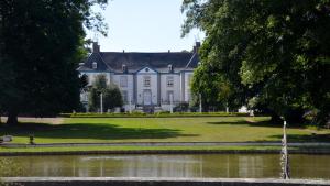 a large white house with a pond in front of it at Vakantiewoning Bisonder in Bilzen