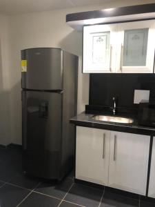 a kitchen with a black refrigerator and a sink at Apartamentos Claudia María in Barbosa