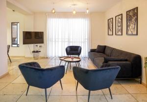 ein Wohnzimmer mit einem Sofa, Stühlen und einem Tisch in der Unterkunft YalaRent Fruit Tree Villa with Private Pool in Eilat