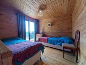 1 dormitorio con 2 camas en una cabaña de madera en Hermosa y cómoda cabaña con vista al lago, en Vichuquén