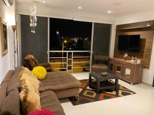 a living room with a couch and a large window at Franches Apt, Amplio apartamento Familiar amoblado, San Lorenzo Salinas in Salinas