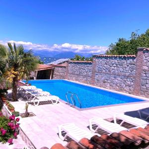 a swimming pool with lounge chairs next to a stone wall at Boutique Hotel Talaveri In Telavi in Telavi