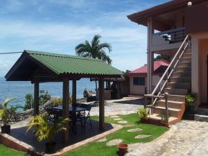 a house with a table and chairs next to the ocean at Sunset Vista Sea Front Guest House in Camotes Islands