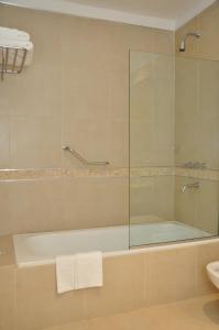 a bathroom with a tub and a glass shower at Howard Johnson Hotel Piedras Moras in Almafuerte