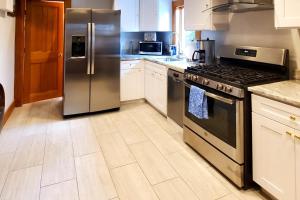 una cocina con electrodomésticos de acero inoxidable y armarios blancos en Nautical Daze, en Oak Bluffs