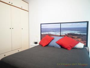 a bedroom with a bed with red and blue pillows at EL HOGAR DEL MAGEC in Las Palmas de Gran Canaria