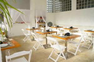 a room with wooden tables and white chairs at Villa Amado in Morro de São Paulo