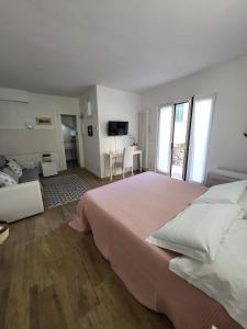 a white bedroom with a large bed and a television at Residenza Solferino in Corniglia