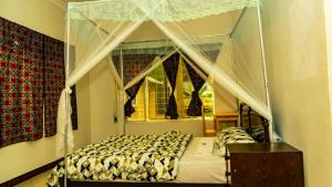 a bedroom with a canopy bed and a window at Pazuri House Iringa in Iringa