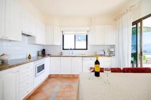 una cocina blanca con 2 copas de vino en una mesa en Villa with Private Pool, Jacuzzi & 360° Sea Views, en Callao Salvaje