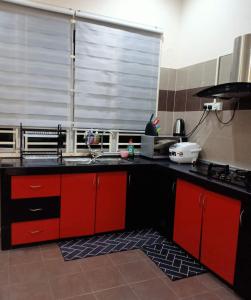 a kitchen with red cabinets and a large window at Melissa Homestay Merlimau in Merlimau