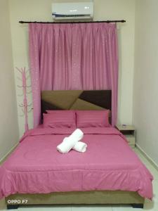 a pink bed with two white towels on it at Melissa Homestay Merlimau in Merlimau