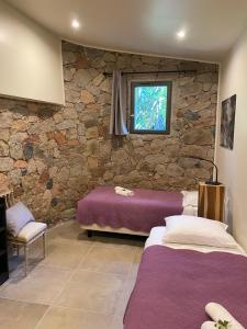 two beds in a room with a stone wall at Maranatha, front de mer avec plage in Porto-Vecchio +240 photos