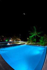 uma piscina azul à noite com palmeiras em Villa Amado em Morro de São Paulo