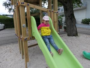 Una bambina che scivola giù da uno scivolo su un parco giochi di Landgasthof Spitzerwirt a Sankt Georgen im Attergau