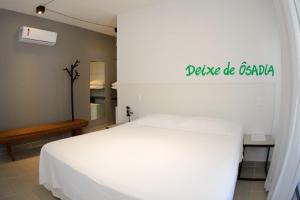 1 dormitorio con 1 cama blanca y un cartel en la pared en Villa Amado, en Morro de São Paulo