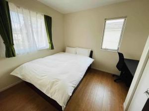 Un pequeño dormitorio con una cama blanca y una ventana en Fujisawa - House - Vacation STAY 88722, en Fujisawa