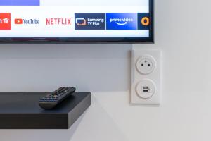 a remote control sitting on a stand next to a tv at Bienvenue à Reims type studio charmant et lumineux 2eme étage in Reims