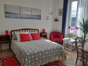 ein Schlafzimmer mit einem Bett mit zwei roten Kissen in der Unterkunft Studio Neptune in Arromanches-les-Bains