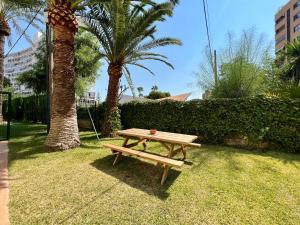 una mesa de picnic de madera en la hierba con palmeras en Apartamento cerca del mar, en Alicante