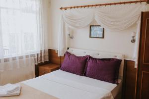 a bedroom with a canopy bed with purple pillows at Kervansaray Hotel in Pamukkale
