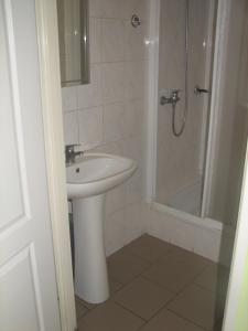 a white bathroom with a sink and a shower at Zajazd Markowski in Bojanowo