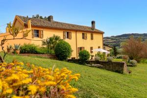 una grande casa gialla su una collina erbosa di B&B Glicine ad Ancona