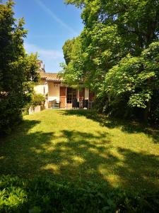 a house with a large yard with trees in front of it at Chez Eliane in Villeneuve-la-Comptal