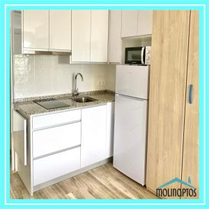 eine weiße Küche mit einer Spüle und einem Kühlschrank in der Unterkunft Estudio 31 Frente al Mar by Molinaptos in Benidorm