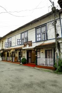 a large white building with black windows on a street at Walton's Homestay, Fort Cochin in Fort Kochi