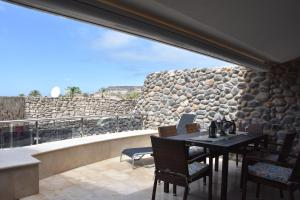 un patio con mesa, sillas y pared de piedra. en ELSA TAURO TOPAZ en Mogán