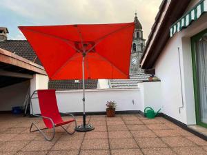 a red chair and an umbrella on a patio at Appartamento Ascona , rooftop terrace apartment in Ascona