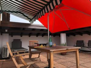 a wooden table with a red umbrella on a patio at Appartamento Ascona , rooftop terrace apartment in Ascona