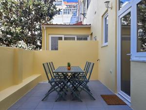 a table and chairs on a patio with a yellow wall at Exotic Fusion: Coffee & Radio in Lisbon