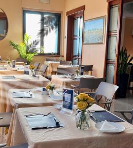 une rangée de tables dans un restaurant avec des fleurs dans un vase dans l'établissement Hotel Motel Top, à Cusago