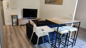 a living room with a table and chairs and a television at Superbe appartement dans résidence avec piscine in Toulouse