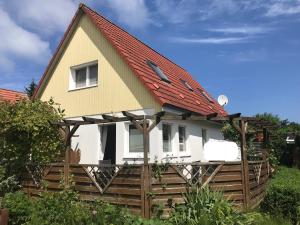 a house with a red roof and a wooden fence at Ferienhaus Strandgut in Zingst