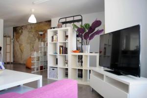 a living room with a tv and a white book shelf at Chalet con Piscina y BBQ en la Playa in Málaga