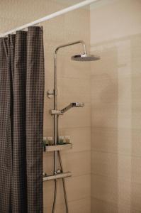 a shower with a shower head next to a shower curtain at Rozenstein design apartment in Brocēni