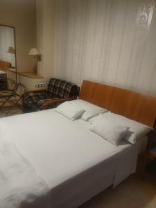 een groot wit bed in een kamer met een bank bij Hostal Burbia in Villafranca del Bierzo