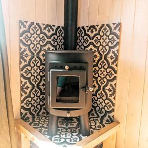 a stove in a room with a wall at Stunning Shepherd's Hut Retreat North Devon in Bideford