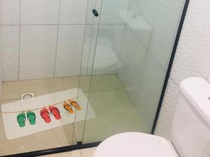 a bathroom with a glass shower with three pairs of glasses at Pousada Cair do Sol in Ilha do Mel