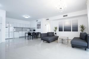 a white living room with chairs and a table at Royal Park By Sun and View in Eilat