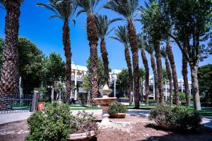 a park with palm trees and a fountain at Royal Park By Sun and View in Eilat