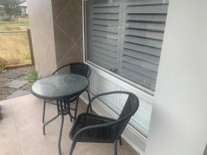 dwa krzesła i stół na balkonie z oknem w obiekcie Huntlee Getaway w mieście Branxton