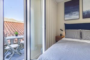 a bedroom with a bed and a balcony with a table at Porta 25 Guesthouse in Covilhã