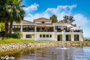 una gran casa blanca con un estanque frente a ella en Nueva Andalucia Magna Marbella Golf, en Marbella