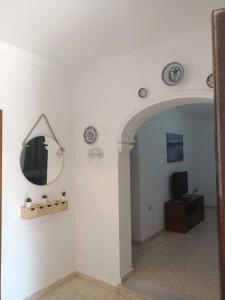 ein Flur mit einem Spiegel und einem Fernseher an der Wand in der Unterkunft Casa Manoli in El Palmar